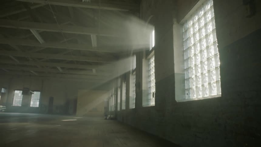 A view of an abandoned building with the sun rays shining through the windows