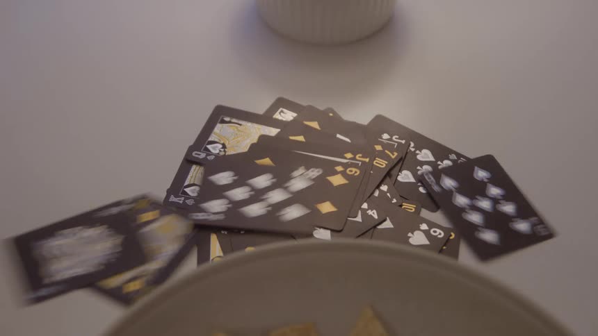 Black playing cards are scattered on the table