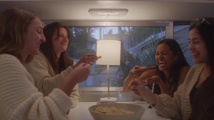 Four women having fun eating nachos at a table