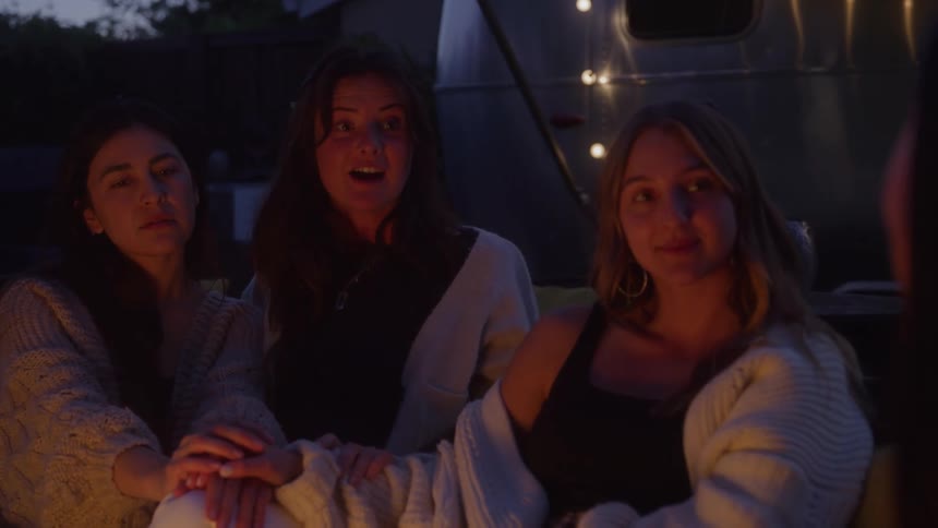 Four women are sitting infront of a bonfire and having a conversation