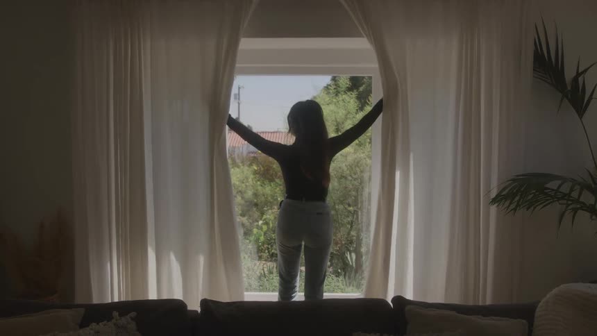 Woman opening the living room curtain