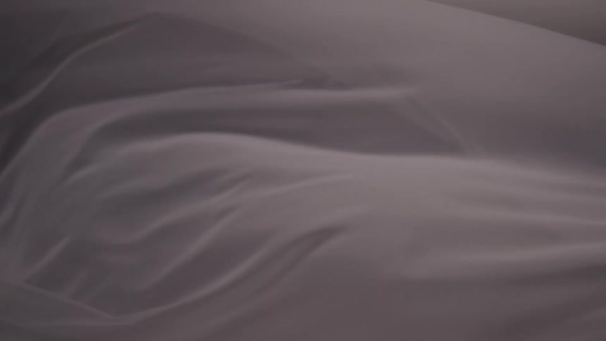 A close view shows the gray sheet covering a persons body as the fabric slowly shifts