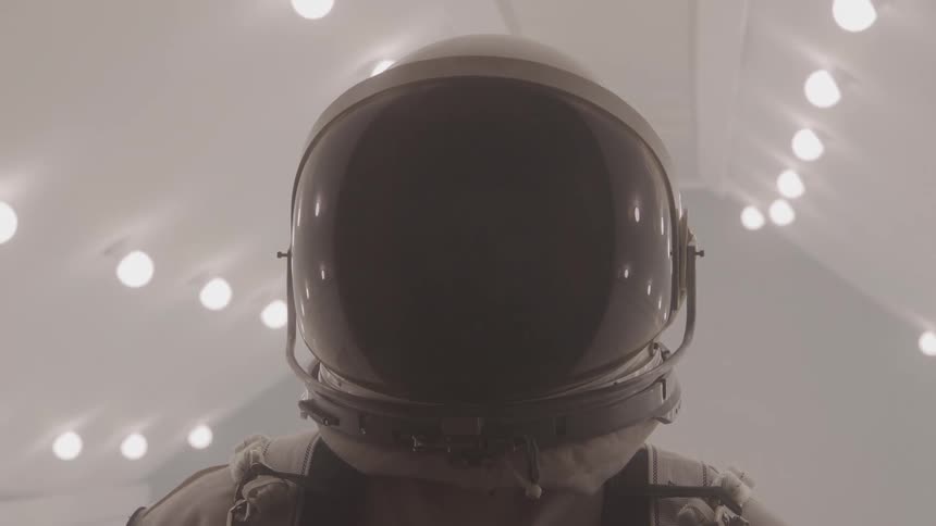 Astronaut with visor reflecting lights stands still
