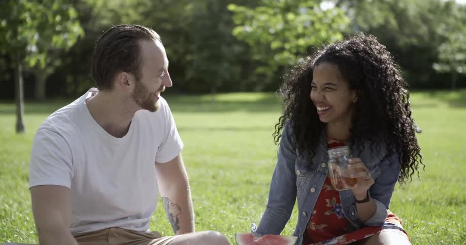 Man and woman drinking out of jars outside at a picnic