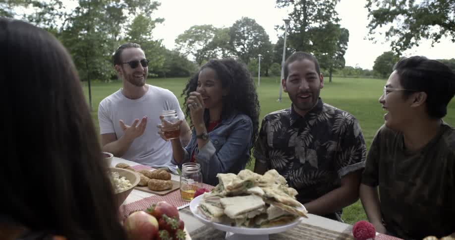 Group of men and woman laughing together outside at a picnic