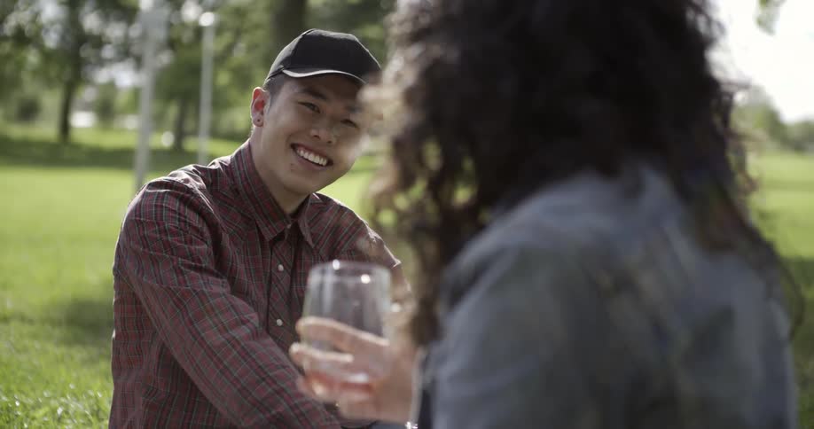 A man and woman drink outside while talking
