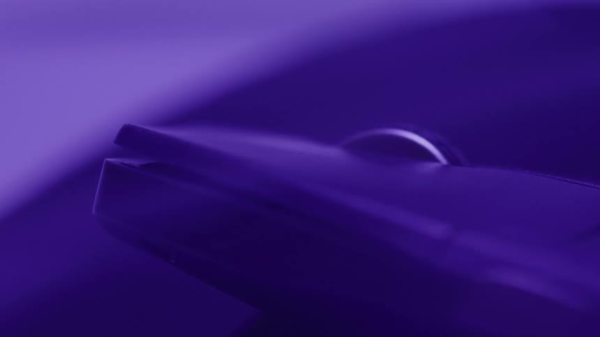 The video shows an abstract closeup shot of an item the lighting shifts between vibrant purple and green