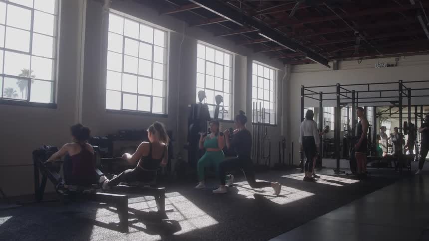 Individuals workout at a busy gym during the daytime