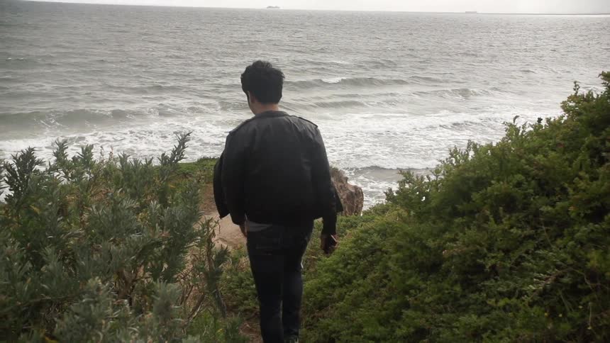 Man walking down a hill towards the shore