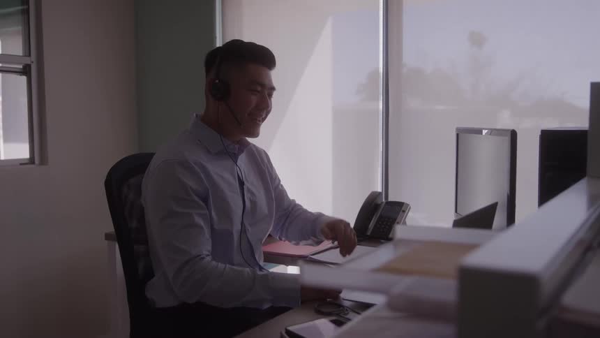 A smiling call center operator at his office desk with a headset