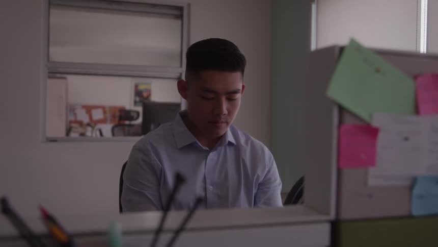 The man is looking down at his desk in the office