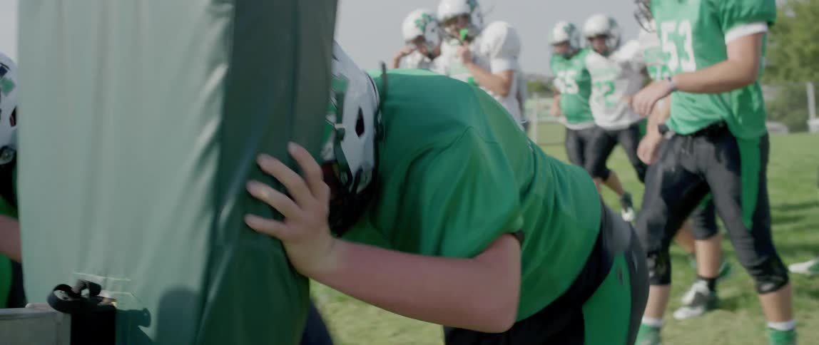 Football players push the pads down the field during practice