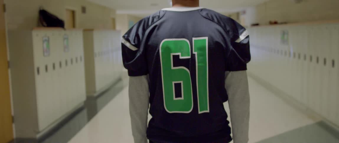 Athlete in american football jersey walking down university hallway