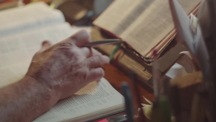 A close up shot of a person hand writing something in a book in an indoor setting