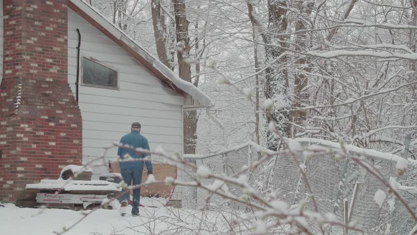 A man walks outside his house in the snow