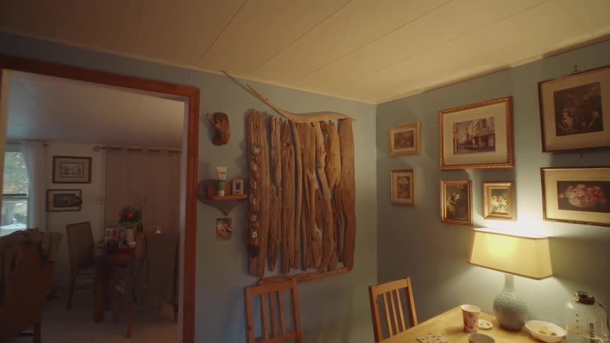 Dining room lit with a wooden table and decorative frames on the wall