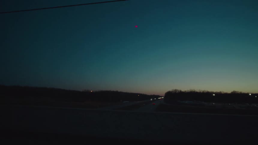 Curved road lit by a streetlight at dusk