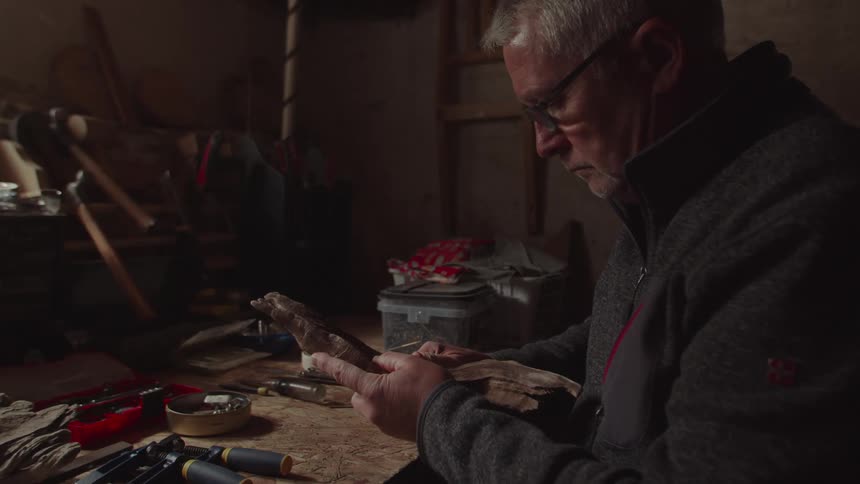 Man with glasses sitting working with an object