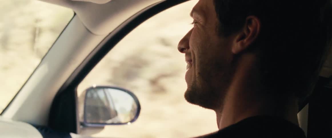 A view of a man smiling as he is riding in a car