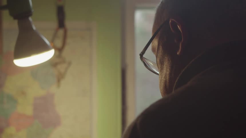 The man is reading something by the window