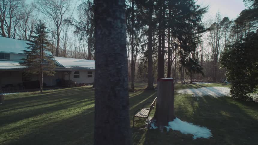 The video shows a person using a camera to film a snowy landscape the camera pans across a snowy field with a forest of bare trees in the distance the lighting is bright and the weather appears to be cold