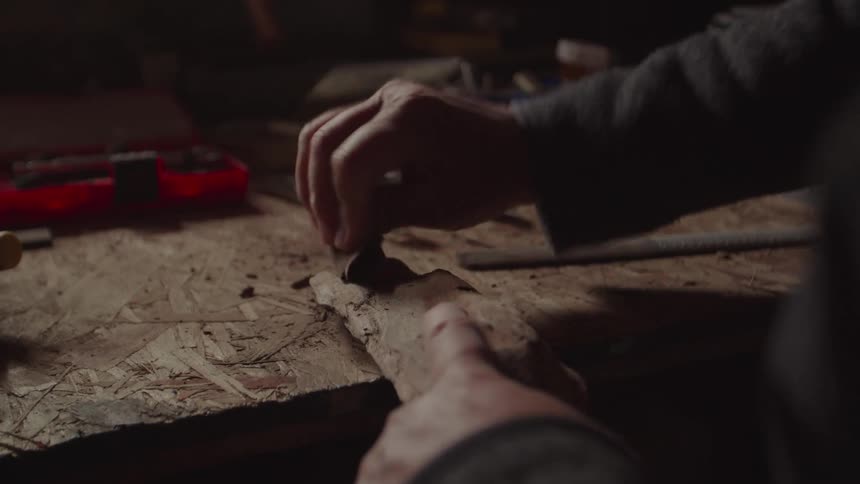 Pair of hands with a chisel carving wood