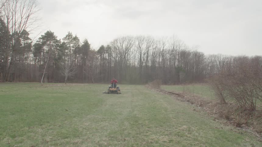 Man driving a lawn mower tractor in an open field