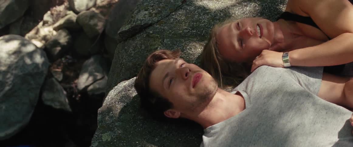 Man and woman smile and lay on a rock