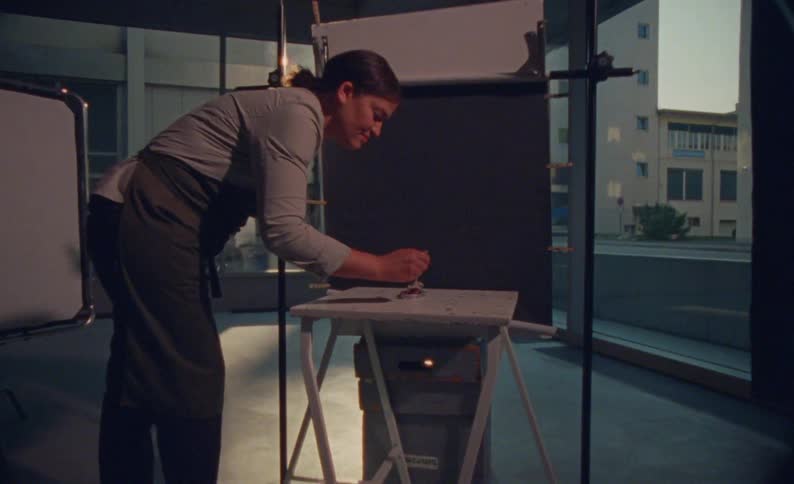 Woman leaning over preparing something on a small table