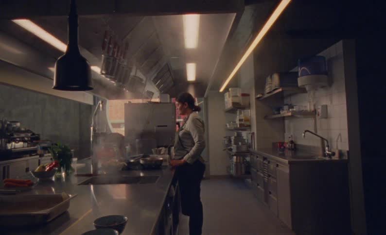 The video shows a chef standing in a commercial kitchen observing a pan on the stove the kitchen is welllit with professionalgrade stainless steel equipment and hanging pots