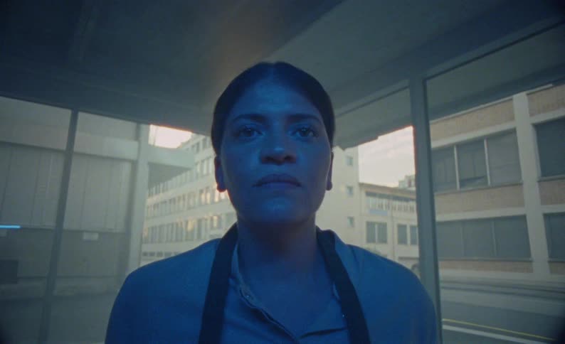 The woman is standing by the window in the building