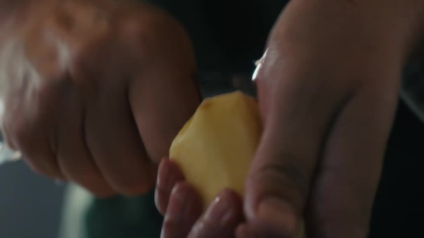 Hands holding and peeling a piece of fresh ginger