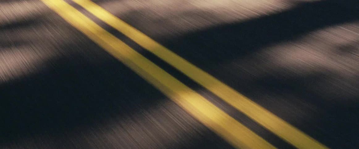 A vehicle is passing the yellow lines in the road