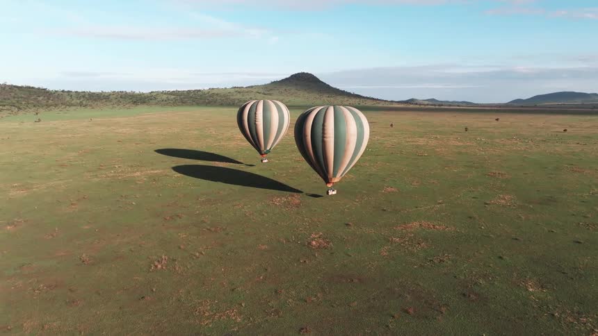 Two hot air balloons float over the field