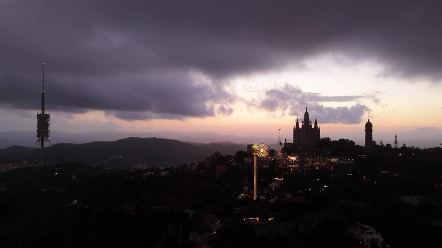 Amusement park with a ferris wheel lit up next to a church on the hill