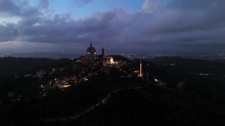 Highway winding up a hill leads to a theme park while fog covers the city in the distance on a cloudy evening