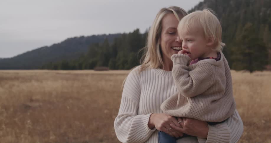 Mother kisses her daughter on the face in an open field