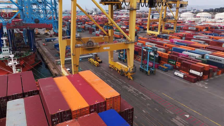 Based on the video a large port is bustling with activity it is filled with thousands of shipping containers in various colors and large cranes are visible moving them