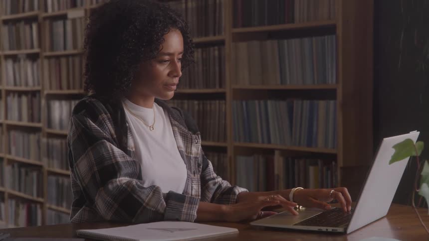 Woman typing on a laptop inside a library