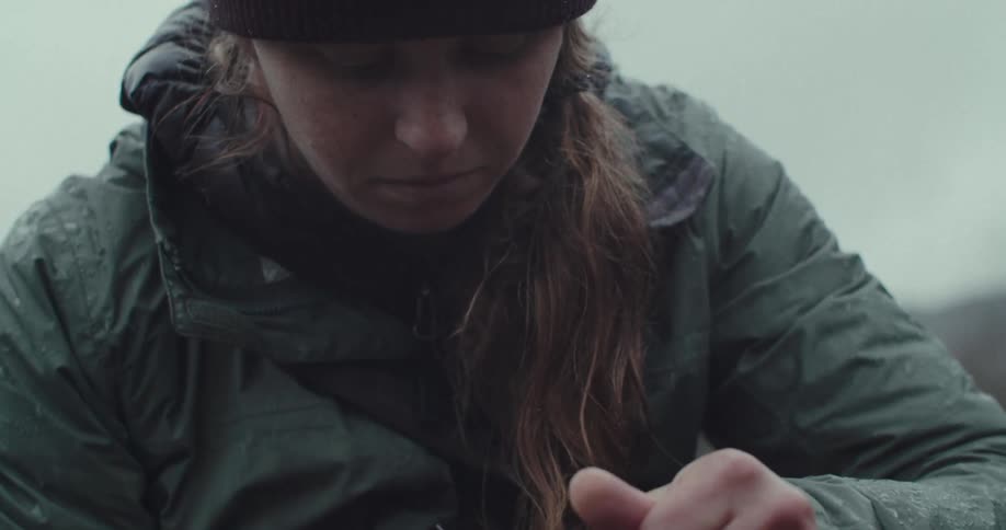 A persons hands work with a fishing line the camera then shows the persons face as they concentrate on the task