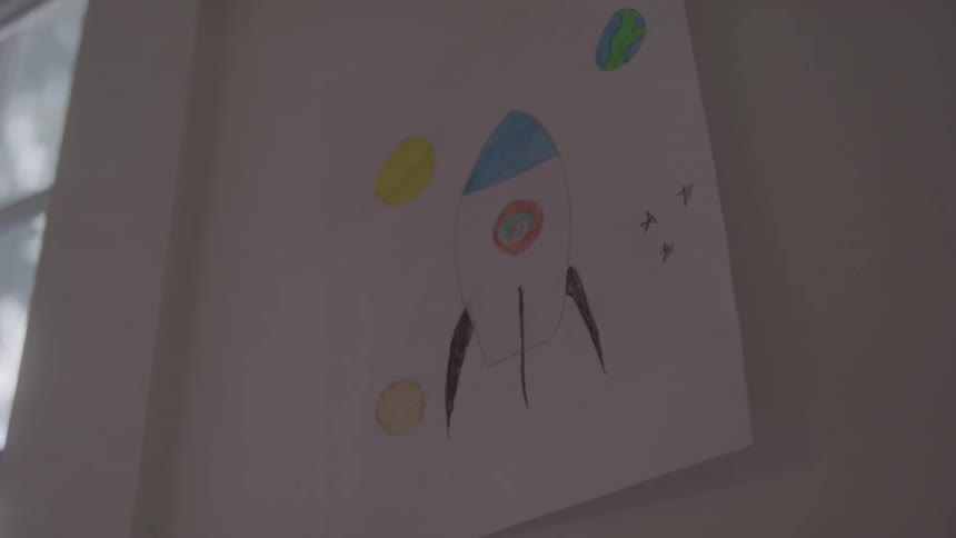 Childs drawing of a rocket with planets taped to the wall