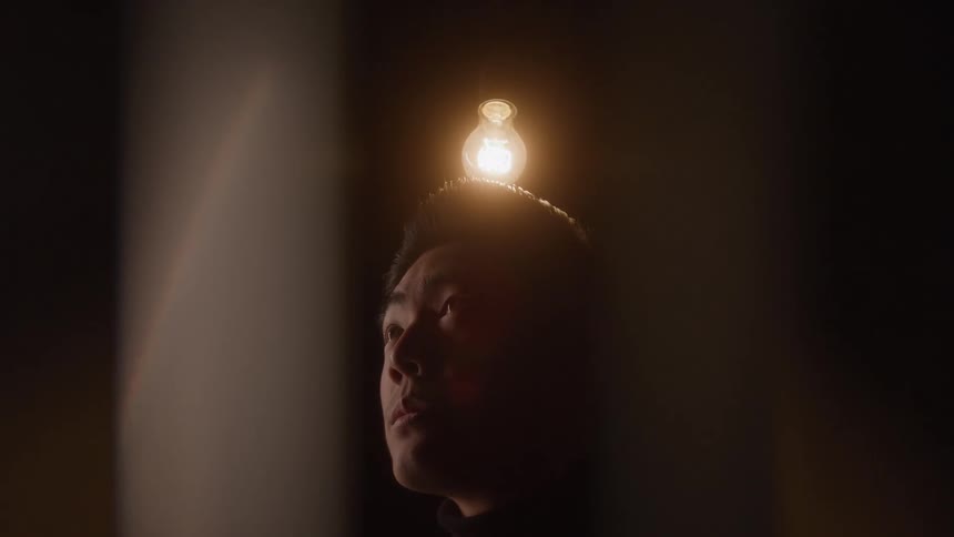 Man looking up with a lit light bulb above his head