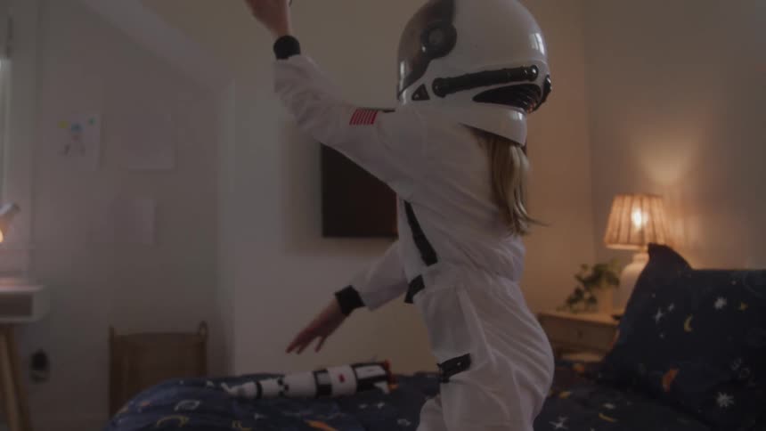 Girl dressed as an astronaut playing with a toy rocket