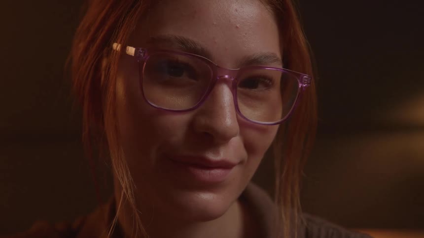 The camera shows a womans face as she looks forward and smiles