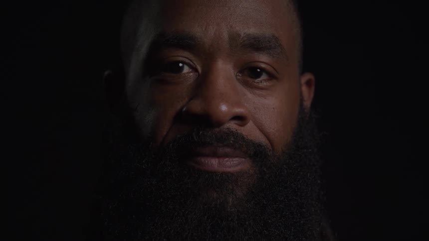 The camera shows a mans face as he turns his head to look at the camera and smiles