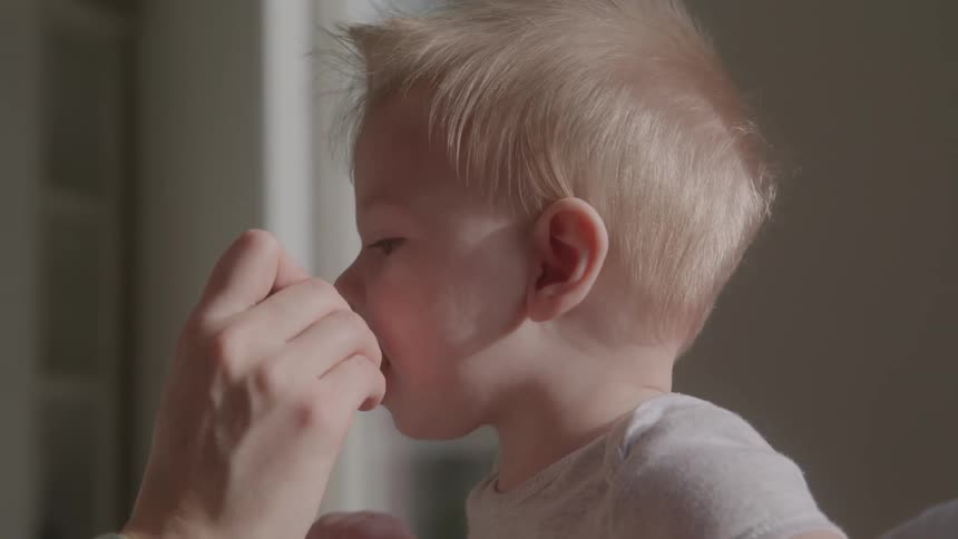 Adult hand feeding a small blonde child