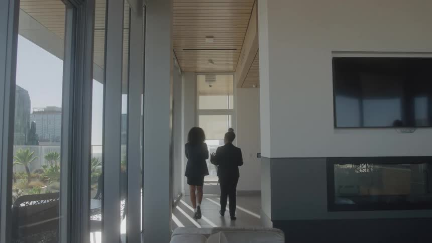 Two women in formal wear walking down a hallway