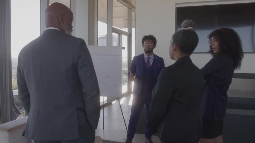 A group of people in business attire has a conversation in an office