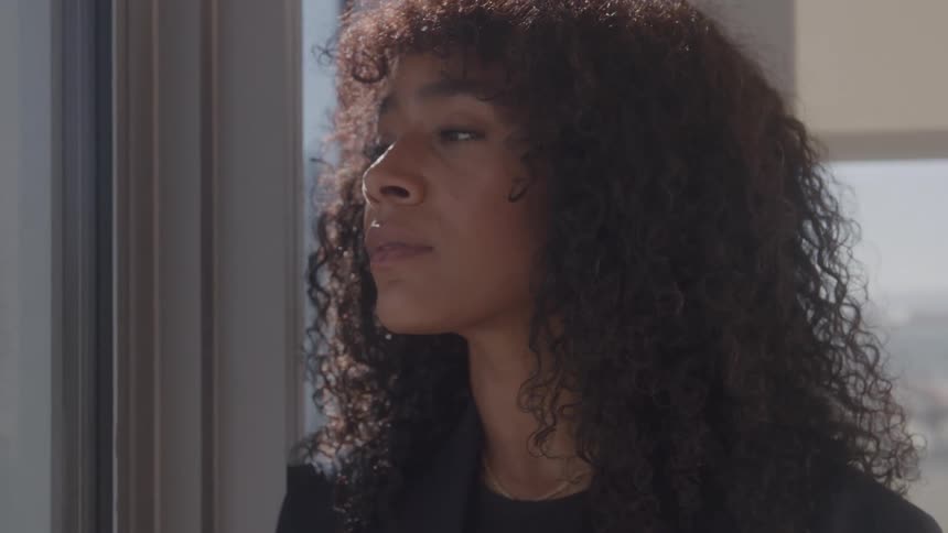 The woman peers out the office window