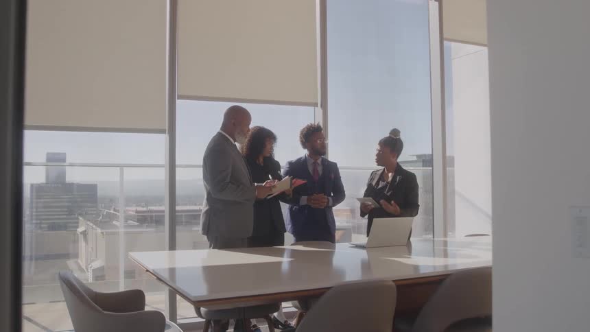 People are having a meeting in the conference room and they are standing and talking